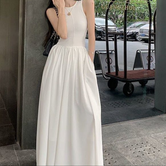 Elegant woman in a sleeveless white long maxi dress, showcasing a high waist and full skirt design, perfect for summer.