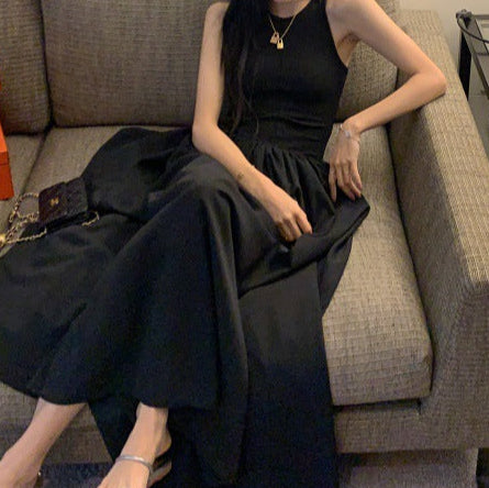 Woman in a long black maxi dress sitting on a sofa, perfect for summer fashion.